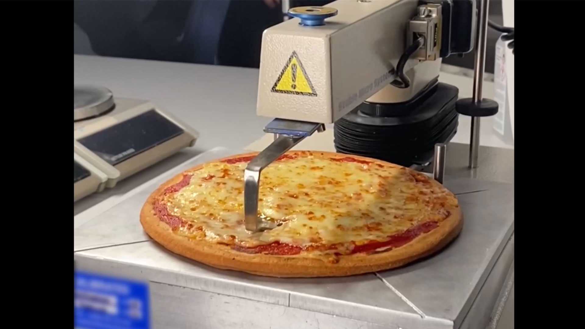 Maskine der tester, hvor strækbar mozzarellaen på en nybagt pizza.