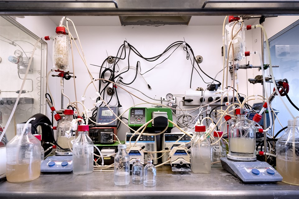 Laboratorieopsætning af bioreaktor med et sammensurium af glasbeholdere, kolber, ledninger, vægte og væsker